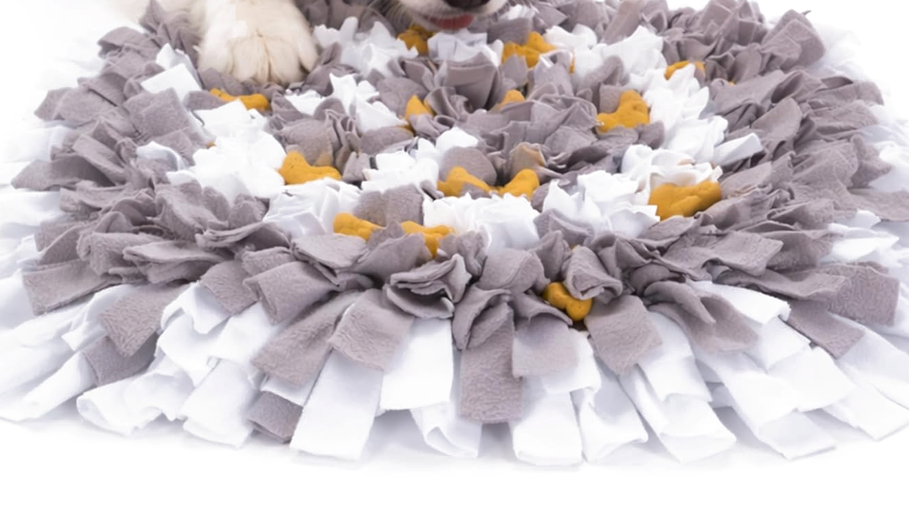 Dog nosing a grey and white snuffle mat with hidden treats