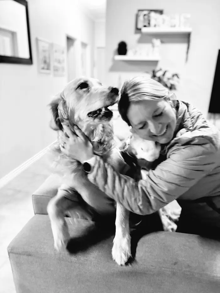 Anelda hugging Lana the golden retriever, both smiling in the hallway at home