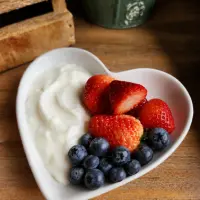 Heart-shaped bowl of yoghurt with strawberries and blueberries
